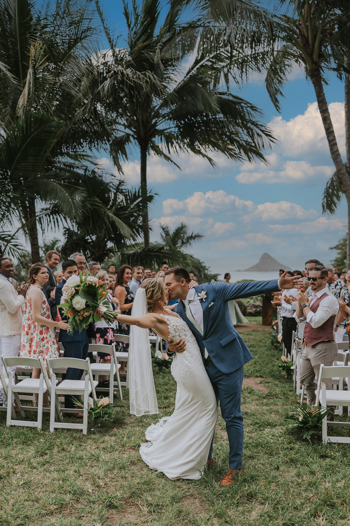 a couple kissing down the aisle at kualoa ranch paliku gardens after ceremony
